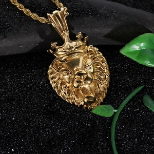 Close-up of golden crown lion head pendant necklace on a dark textured surface