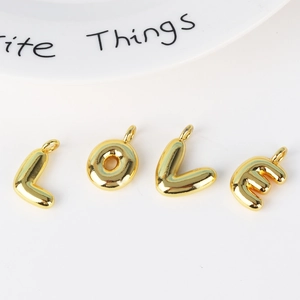 Close-up of polished gold 26-letter pendants L-O-V-E on a clean white surface