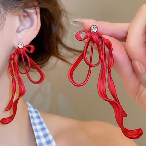 Detail shot of a red ribbon tassel earring with a sparkling cubic zirconia stud accent