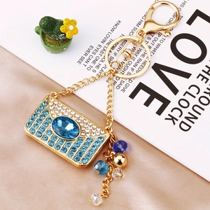 Macro shot of gold envelope charm keychain with blue rhinestones on satin background