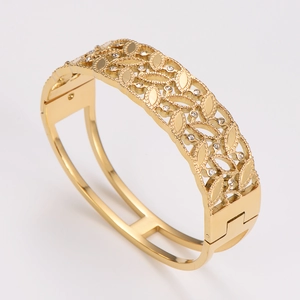 Detailed macro view of gold-plated stainless steel hollow bangle with inset crystals