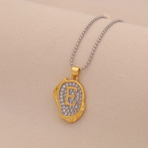Macro shot of silver ball chain with gold letter E pendant encrusted with clear crystals