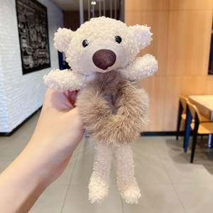 Gros plan d'un ours en peluche beige attaché à un chouchou élastique marron et duveteux