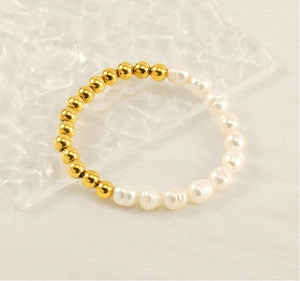 Détail de bracelet perles d'eau douce avec billes dorées sur plateau en verre ondulé