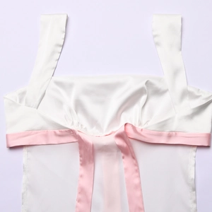 Detailaufnahme eines weißen Satin-Tops mit rosa Schleife und glatter Stoffoberfläche