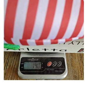 Vue détaillée du chapeau d'elfe de Noël rayé pesé sur une balance numérique à 140g