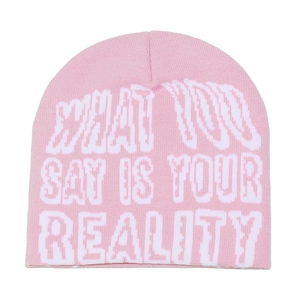 Detail of pink knitted beanie featuring white jacquard slogan in a pixelated street style
