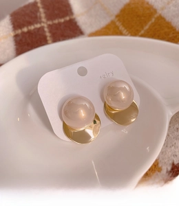 Macro shot of elegant round pearl earrings with golden circular metal studs and silver pins