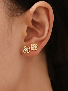 Close-up of gold clover stud earrings with 5A zircon inlay worn by a model