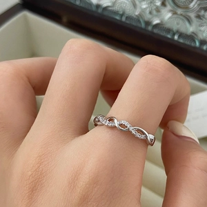 Close-up of infinity twisted ring with micro-pave cubic zirconia on a warm background