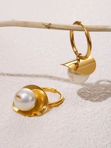 Detail of 18k gold plated hoop earrings with white pearls hanging on a rustic branch