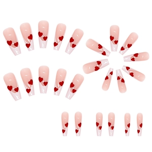 Detail of nude press-on nails with red heart patterns arranged in rows and a circle