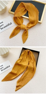 Detailed close-up of bright yellow pleated silk scarf showing fine texture and glossy finish