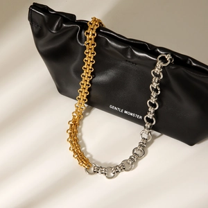 Zweifarbige Kette in Gold und Silber an schwarzer Ledertasche mit Markenbeschriftung