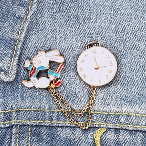 Detail of bunny and clock chain brooch on denim, featuring Alice in Wonderland style