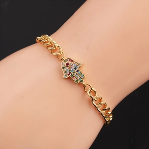 Dettaglio del bracciale Hamsa dorato con pietre colorate su una catena stile cubano