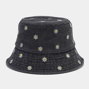 Dettaglio ravvicinato del cappello da pescatore in denim grigio con margherite ricamate