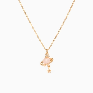 Macro detail of golden Saturn necklace with pink stone planet pendant and star charm