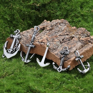 Detailed view of five vintage silver anchor pendants on moss and wood bark background