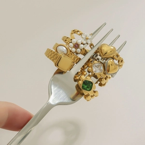 Detailed macro of vintage gold rings with pearls and emeralds on a fork display