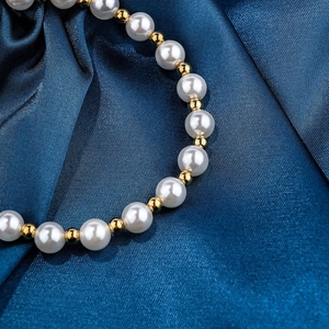 Elegant pearl and gold bead bracelet displayed on a luxurious navy blue silk fabric background