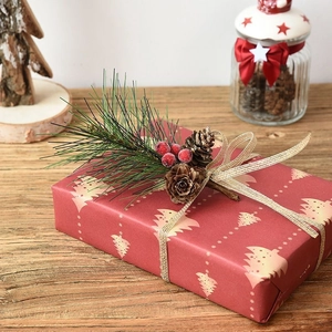 Christmas decoration featuring pine cones, green needles and red berries on a gift box