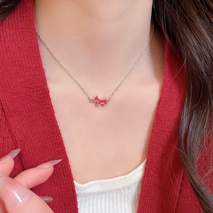 Close-up of a rose gold necklace featuring a red terrier puppy enamel pendant on a model