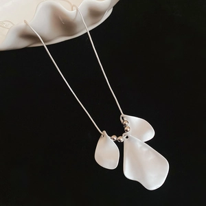 Close-up of a necklace with three white brushed petal pendants and silver metal beads