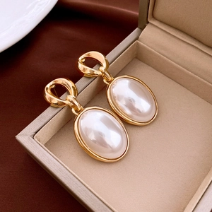 Detail of vintage gold oval earrings with faux pearls displayed in a premium jewelry box
