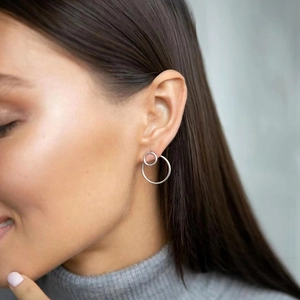 Close-up of model wearing silver double hoop earrings with cubic zirconia stones