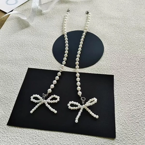 Macro detail of elegant long white pearl drop earrings with decorative pearl bow pendant