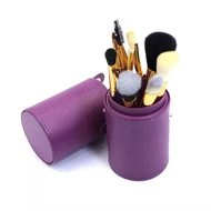 Detail of 7-piece purple makeup brush set with storage tube and gold ferrules on white background