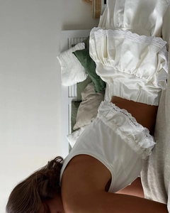 Detail of white two-piece lounge set featuring lace trim on sleeveless top and elastic shorts
