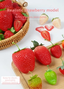 Detailed view of realistic artificial strawberry models with sliced halves and green leaves