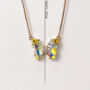 Macro shot of iridescent crystal butterfly pendant on a delicate gold box chain
