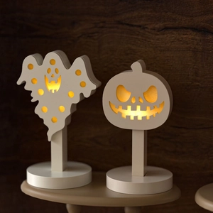Close-up of Halloween ghost and pumpkin LED silhouette lights with warm yellow glow