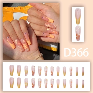 Details von langen Ballerina-Nägeln mit orangefarbenen Gänseblümchen und kleinen Strasssteinen