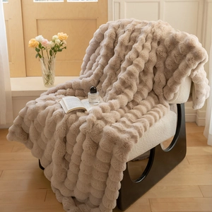 Detailed texture of apricot faux rabbit fur blanket with 3D dotted pattern on a modern chair