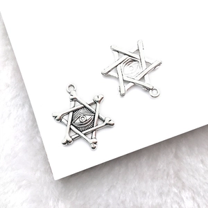 Detailed view of silver Eye of Horus hexagram pendants on white plush background