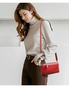 Close-up of red genuine leather crossbody bag texture and metal zipper details