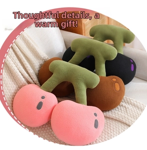 Detail of plush cherry pillows in pink and brown soft fabric on a cozy knitted blanket