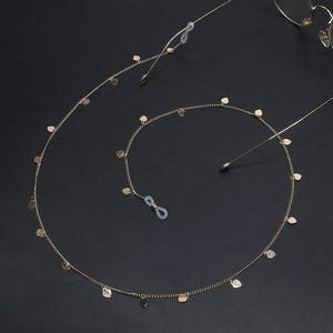 Macro view of golden eyewear chain featuring delicate heart-shaped metal pendants