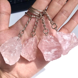 Detailed view of four natural raw pink crystal stone keychains with silver metal rings