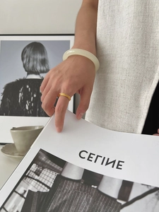 Detail of light green matte resin bangle and slim gold frosted ring worn by a model