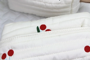 Close-up of white quilted fabric tissue box with delicate red cherry embroidery detail