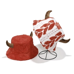 Detail of plush Christmas tree horn bucket hats in red and white festive leaf patterns