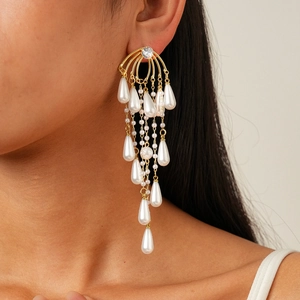 Close-up of gold fringe earrings with zircon studs and pear-shaped pearl tassels
