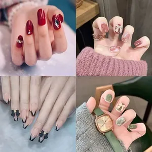 Detail of press-on nails with green cat-eye, red rhinestones, and bow designs