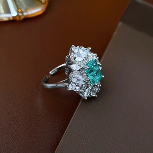 Dettaglio macro di anello regolabile con zircone verde quadrato e pietre taglio marquise