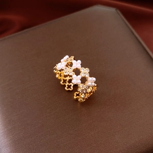 Détail macro d'une bague fleur plaquée or avec perles blanches et zircons brillants
